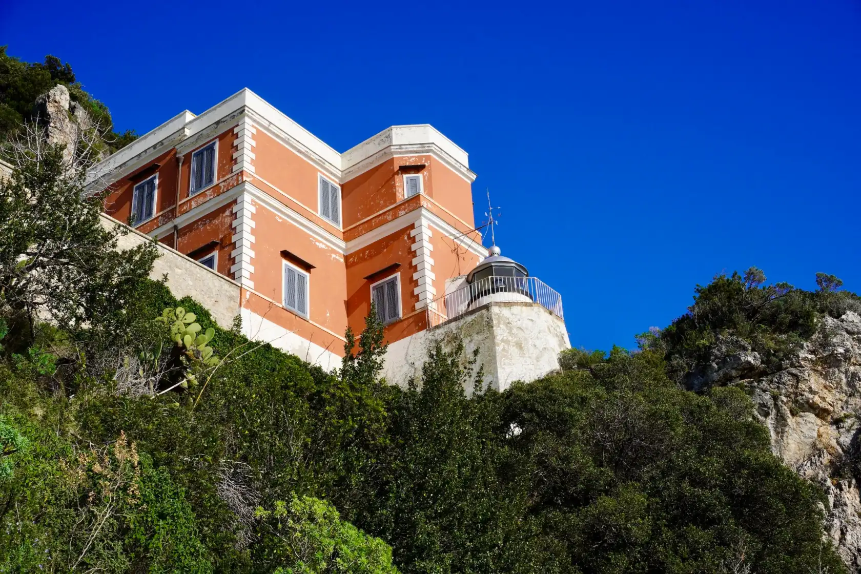 Il Faro di Capo d’Orso visto dal basso, tra la vegetazione della scogliera