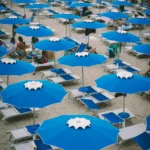 File di ombrelloni blu sulla spiaggia di uno stabilimento