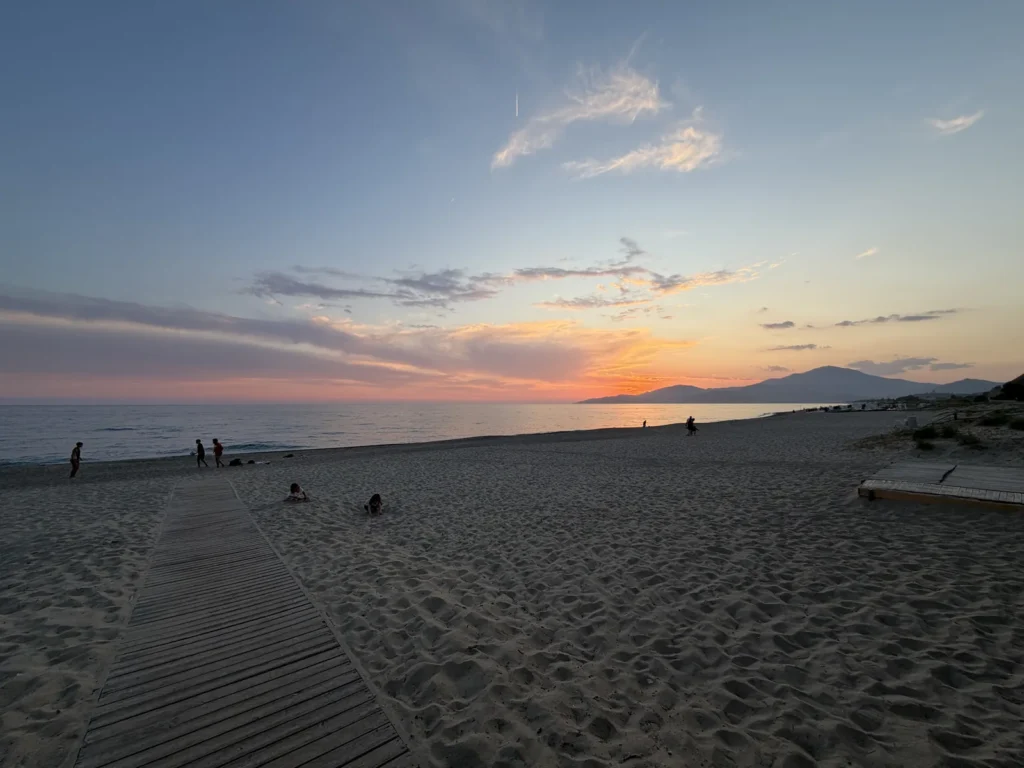La passerella di legno sulla sabbia verso il mare al tramonto