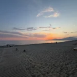 La passerella di legno sulla sabbia verso il mare al tramonto