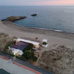 Lo stabilimento sulla spiaggia con la scogliera e il mare, visto dal drone al tramonto