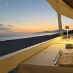 Un tavolo apparecchiato del ristorante sulla spiaggia, con il mare al tramonto