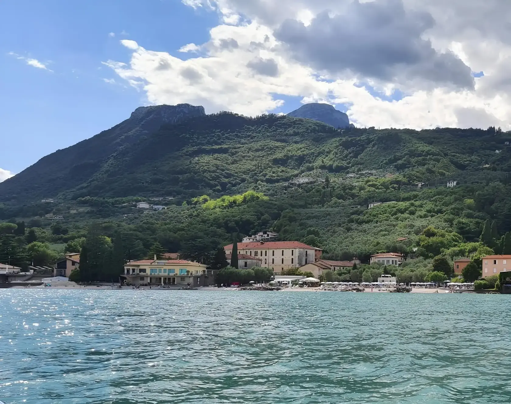 La riva di Bogliaco, a Gargnano, vista dal Lago di Garda con i monti alle spalle