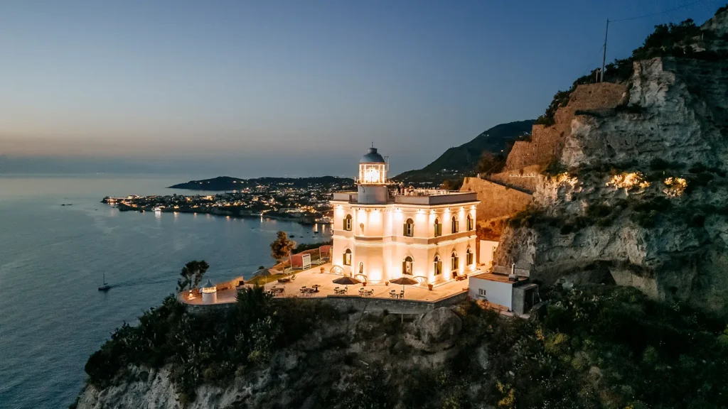 Il Faro di Punta Imperatore illuminato sulla scogliera, all’imbrunire