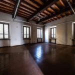 Una sala con il soffitto a travi di legno e cinque finestre