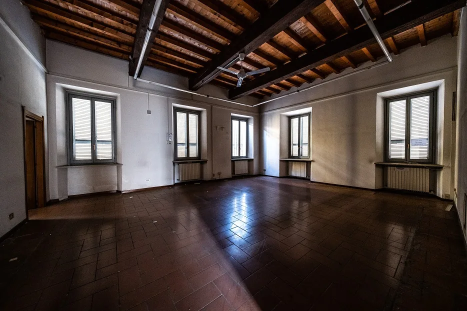 Una sala con il soffitto a travi di legno e cinque finestre