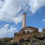 Il faro visto dalle rocce laviche, con le nuvole