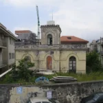Il vecchio faro dietro il muro di cinta, visto dalla strada