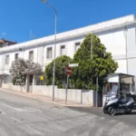 L’ex caserma bianca all’angolo della via, con gli alberi nel cortile