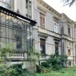 La serra in ferro e vetro sulla facciata, fra la vegetazione