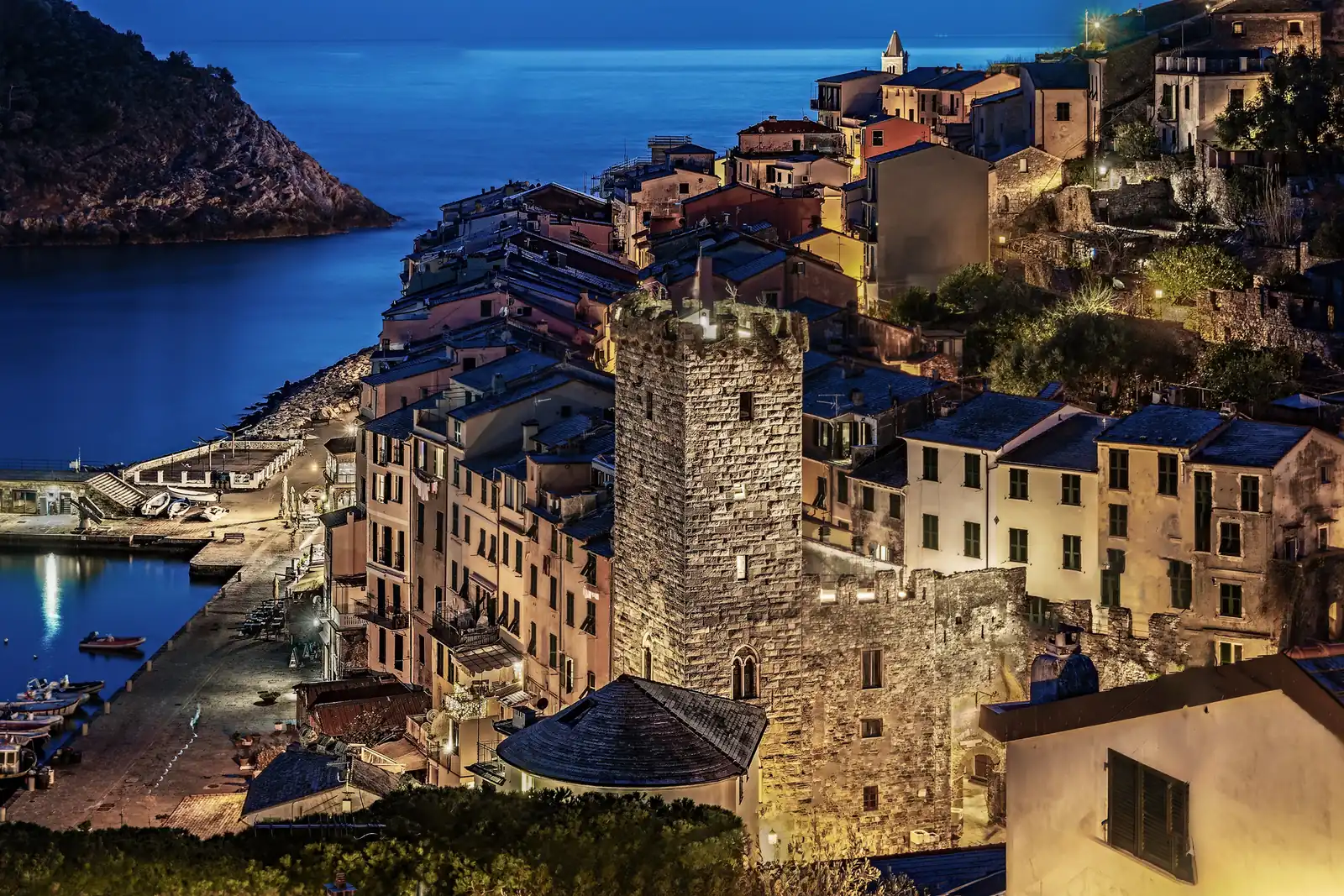 La Torre Capitolare illuminata la sera, fra i tetti del borgo e il porto