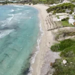 La spiaggia e il mare turchese della baia vicino alla torre, dal drone