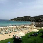 La spiaggia attrezzata della baia con le colline alle spalle