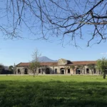 Il parco con uno dei corpi di fabbrica e il Vesuvio sullo sfondo